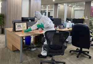 A person wearing a cleaning suit and mask as they disinfect an office.