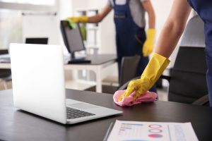 Cleaners using rags to clean down desks and office equipment.