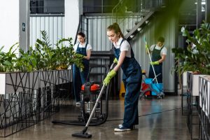 Three cleaners vacuuming and mopping a modern-looking office space.
