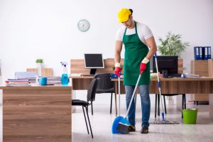 A cleaner sweeping the floor in an office.