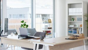 A clean office with a wood desk and big windows.